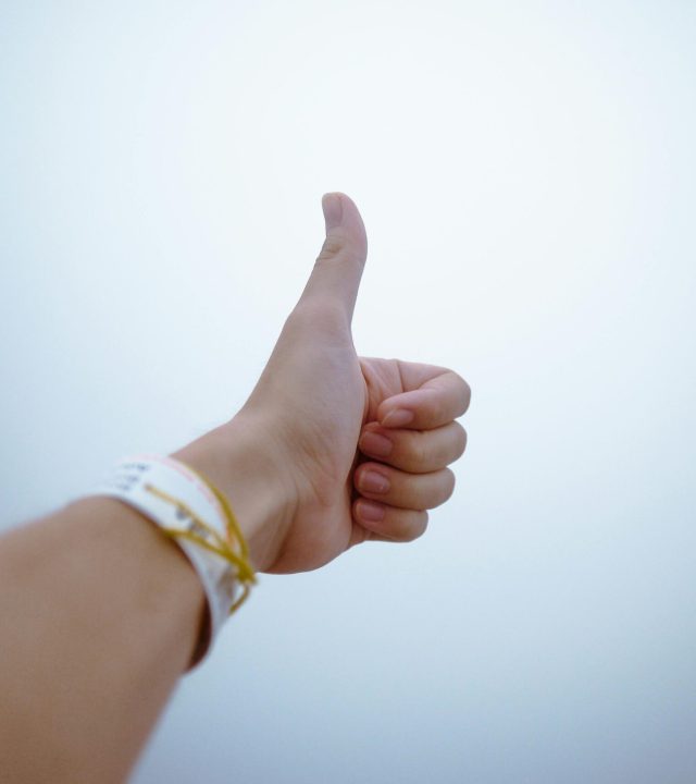 A hand giving a thumbs up gesture symbolizes approval and positivity.