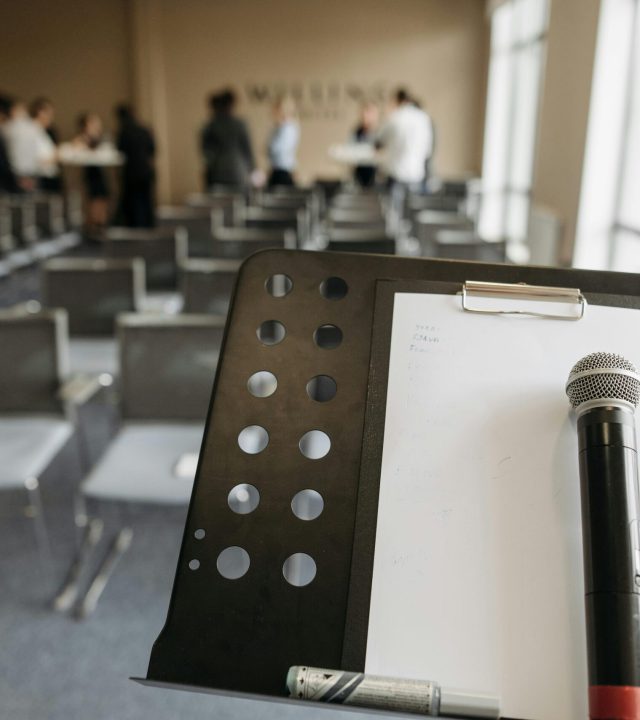 Close-up of a microphone on a stand in a conference room setting.